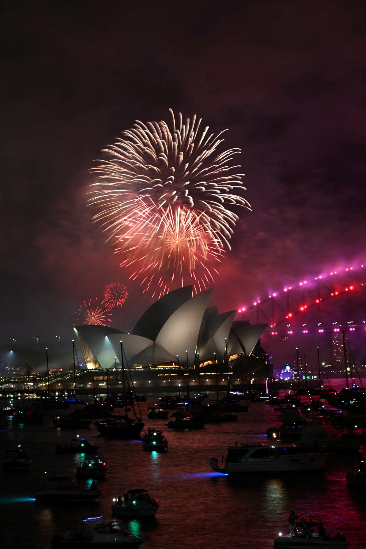 Los "fuegos artificiales familiares" iluminan la Ópera y el Puente del Puerto de Sídney, tres horas antes del espectáculo principal a medianoche en Sídney la víspera de Año Nuevo del 31 de diciembre de 2024. (Foto de Saeed KHAN / AFP)