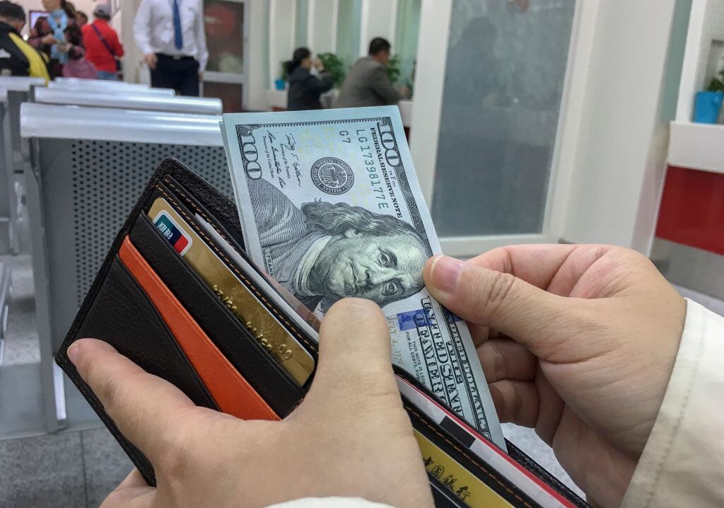 BEIJING, CHINA - 2017/04/18: A Chinese tourist exchange some US Dollar banknotes in a bank, preparing for a travel abroad.  According to the report of UNWTO,  Chinese mainland travelers have spent as high as $261.1 billion abroad,  an increase of 12% over the year of 2015, accounting for about 20.9% of total consumption.  The number of outbound tourists grew by 6%, reaching 135 million. (Photo by Zhang Peng/LightRocket via Getty Images)