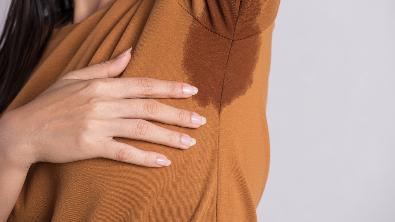 Close-up asian woman with hyperhidrosis sweating. Young asia woman with sweat stain on her clothes against grey background. Healthcare concept.