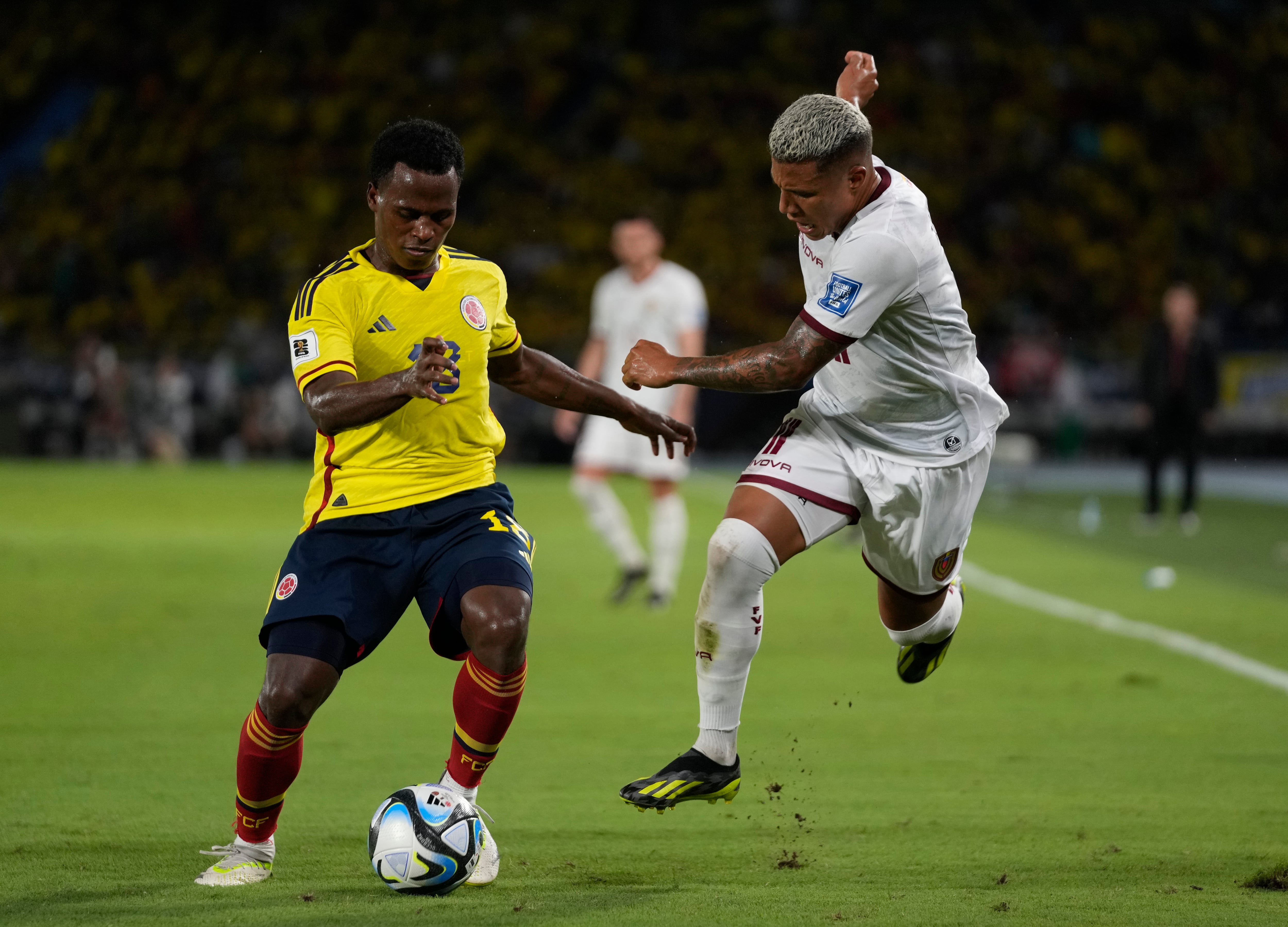 El colombiano Jhon Arias, izquierda, y el venezolano Darwin Machis luchan por el balón durante un partido de fútbol de clasificación para la Copa Mundial de la FIFA 2026 en el estadio Metropolitano de Barranquilla, Colombia, el jueves 7 de septiembre de 2023. (Foto AP/Fernando Vergara)