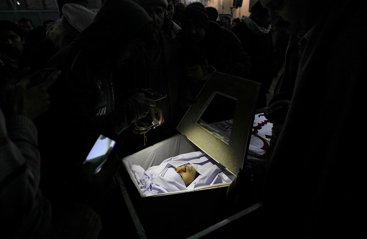 Familiares del estudiante pakistaní Baqir Ali Bangash, de trece años de edad, se reúnen alrededor de su cuerpo. El joven murió durante el ataque talibán a una escuela en Pakistán, este martes, en el que murieron más de 140 estudiantes. (AP)