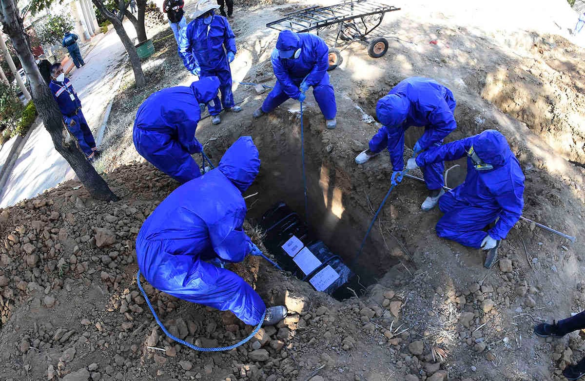 Un ataúd envuelto en plástico que contiene los restos de Cristóbal Huanca Mendoza se baja a una tumba común en un cementerio en Cochabamba, Bolivia, el jueves 2 de julio de 2020. El ataúd de Mendoza está envuelto en plástico como es común en las funerarias cuando se trabaja con covid-19 víctimas o presuntas víctimas del nuevo coronavirus. (Foto AP / Dico Soliz)