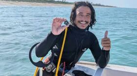 Un buzo muestra una de las monedas recuperadas del tesoro de la Flota española de 1715 en la costa de Florida.