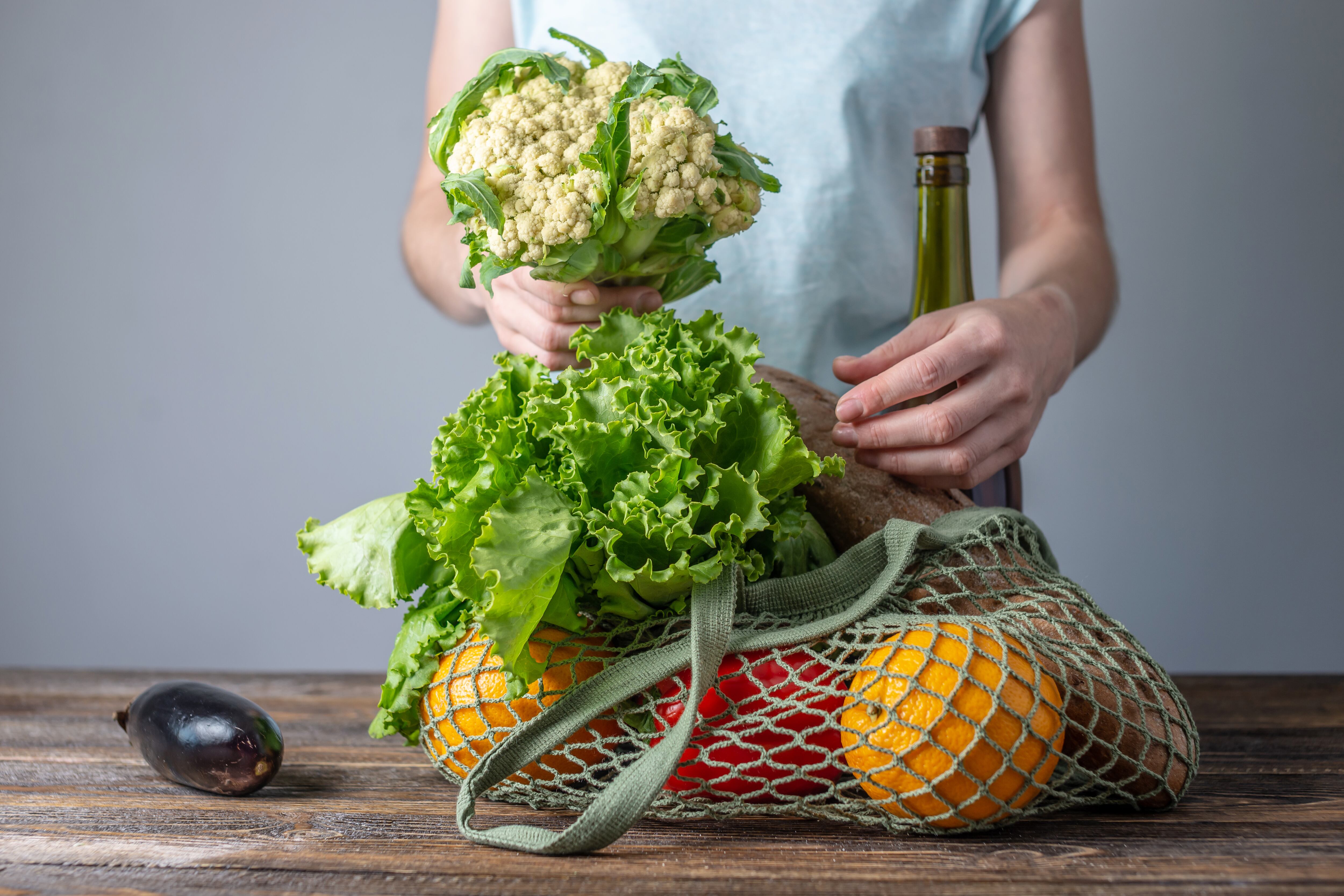 A modern woman is unpacking purchases, pulling products out of a string bag. Concept of eco-friendly behavior, the use of reusable bags and concern for the environment