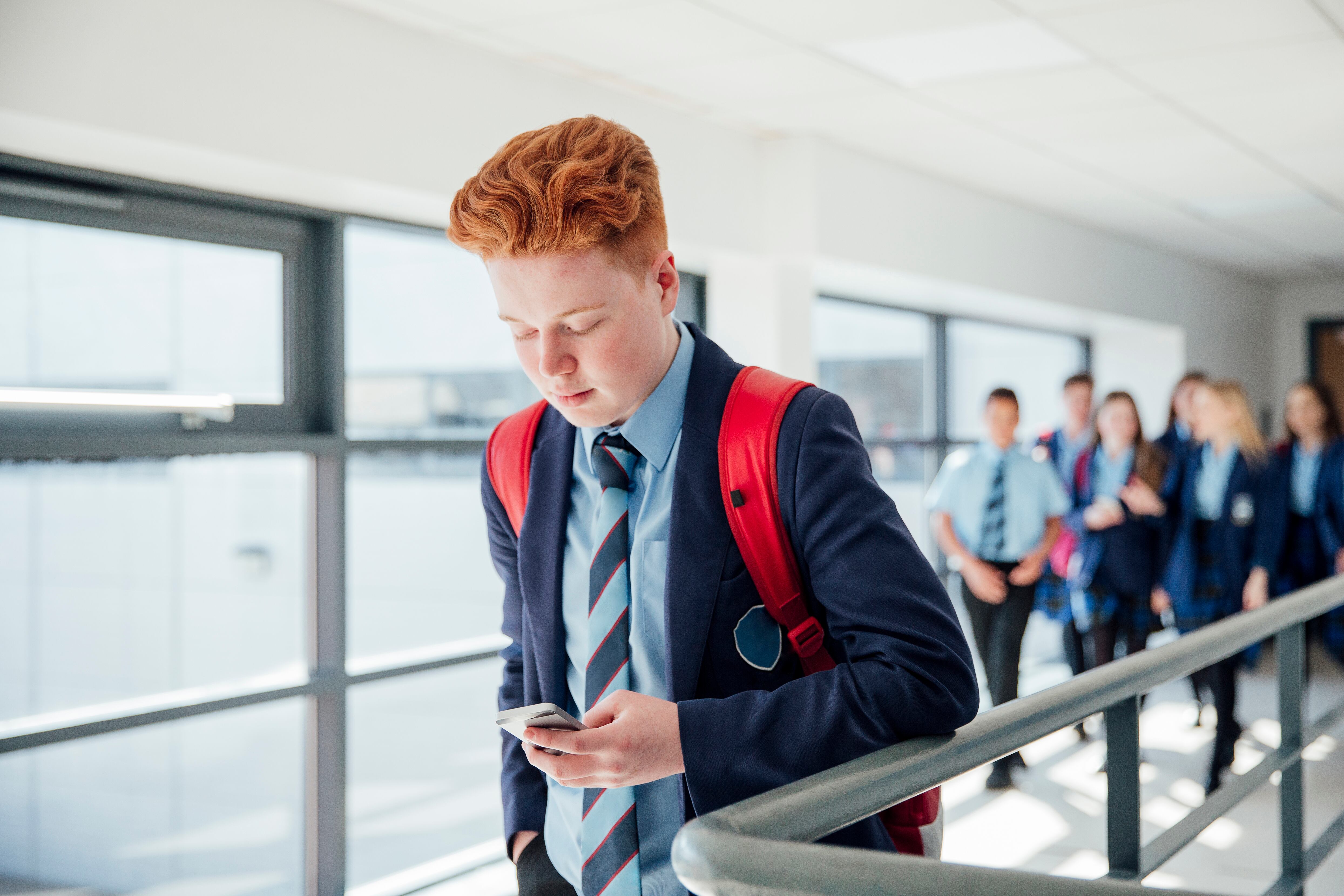 Joven usa su teléfono móvil en el colegio. Imagen de refrencia