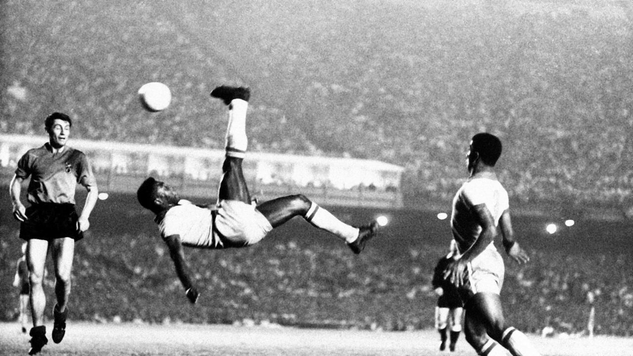 La estrella del fútbol brasileño Pelé patea una pelota en bicicleta durante un partido en un lugar desconocido, septiembre de 1968. (AP Photo File)