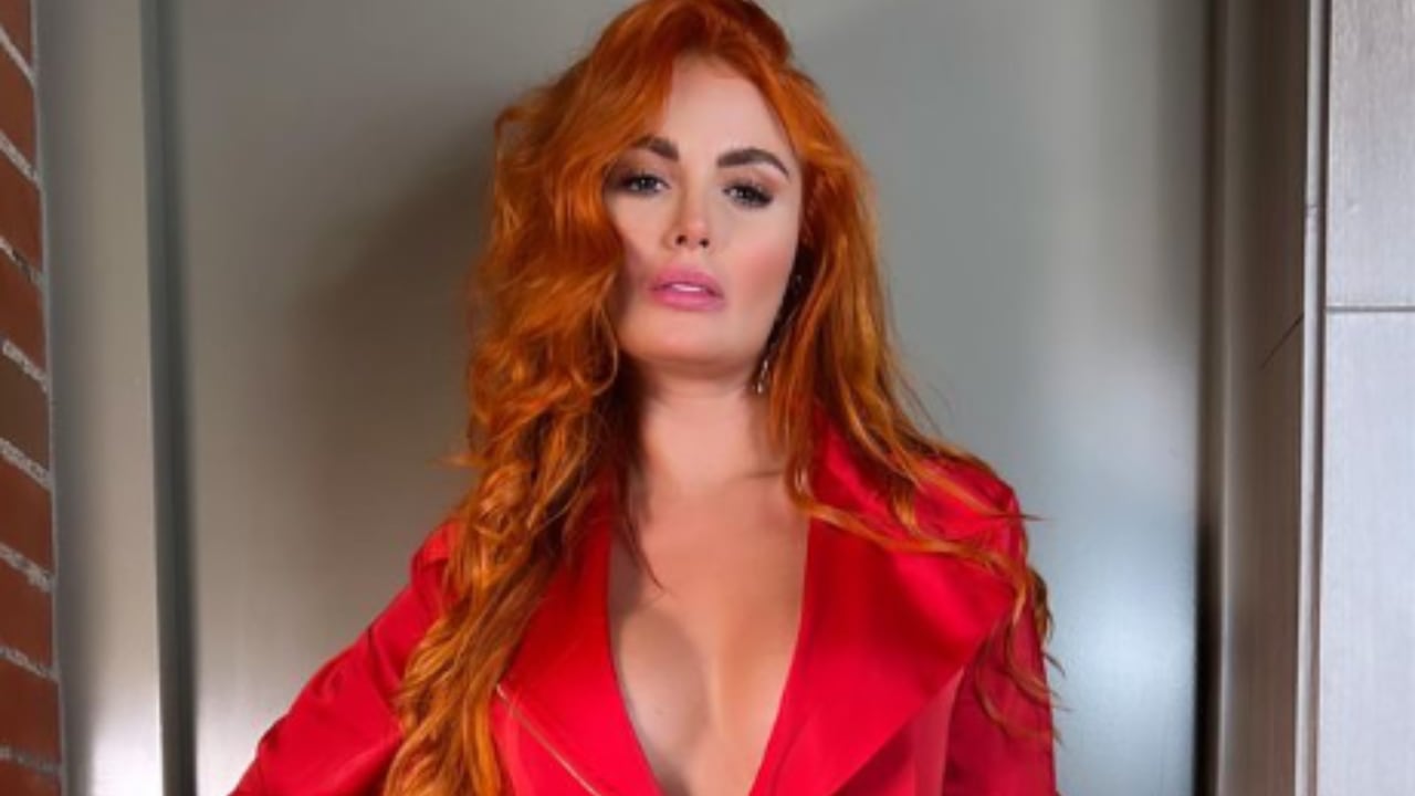 Sara Uribe modelo y presentadora luce un sensual vestido enterizo rojo con un pronunciado escote que resalta se pecho.