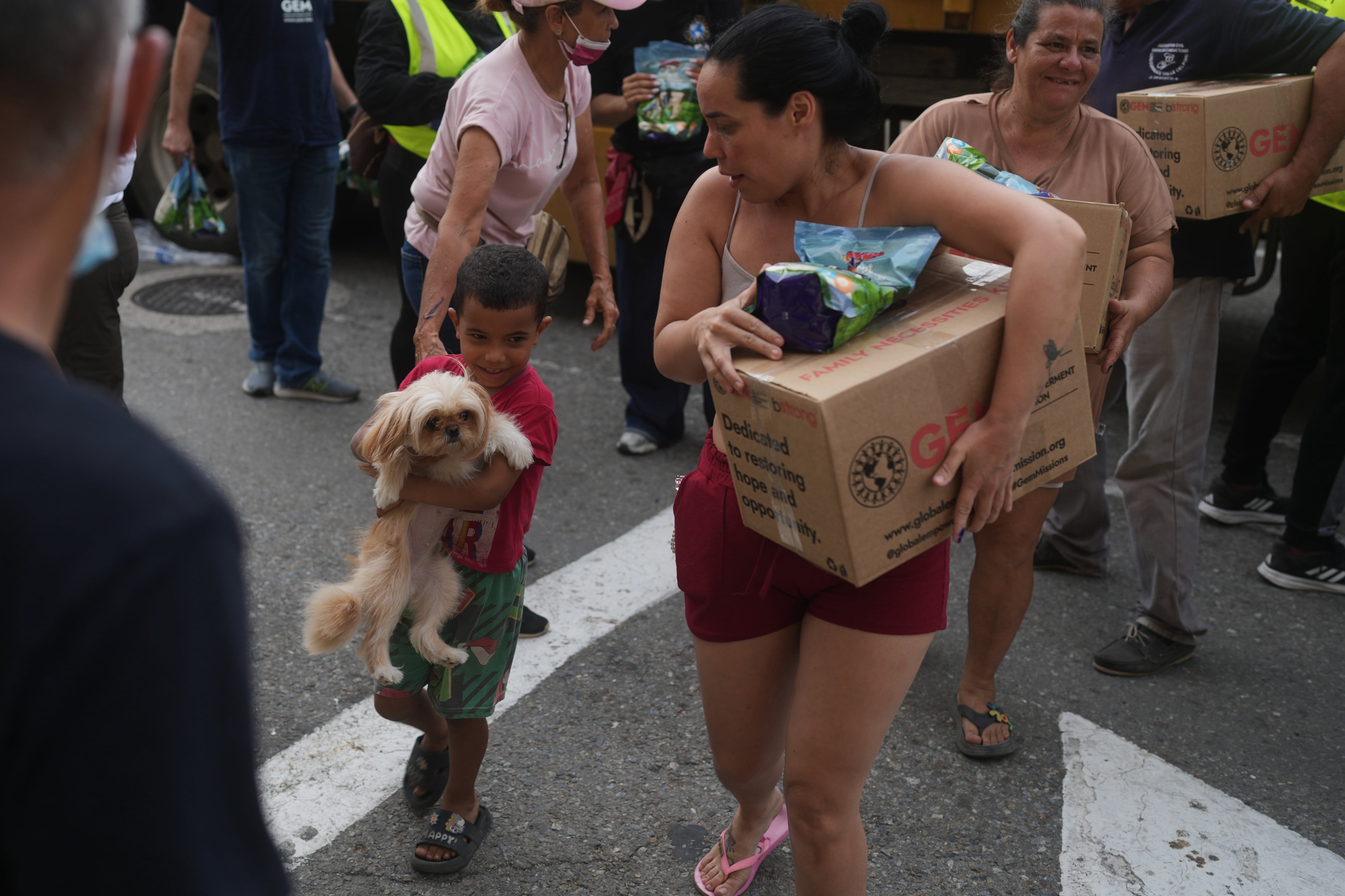 Personas afectadas por los terremotos transportan ayuda humanitaria estadounidense tras recibirla en La Guaira, Venezuela.