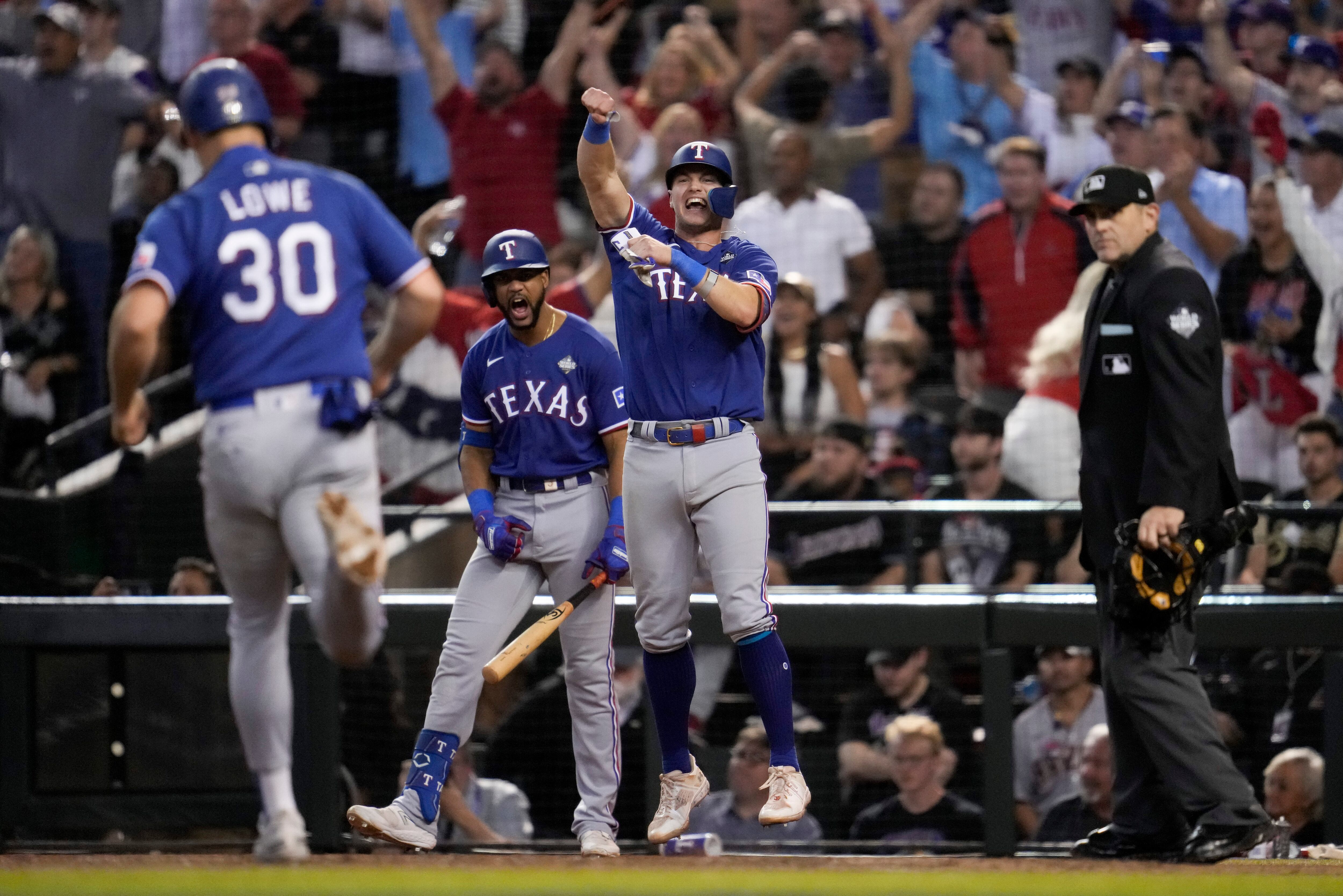 Josh Jung y Nathaniel Lowe (30) celebran después de anotar en un sencillo de Jonah Heim durante la novena entrada en el Juego 5 de la Serie Mundial de béisbol contra los Diamondbacks de Arizona.