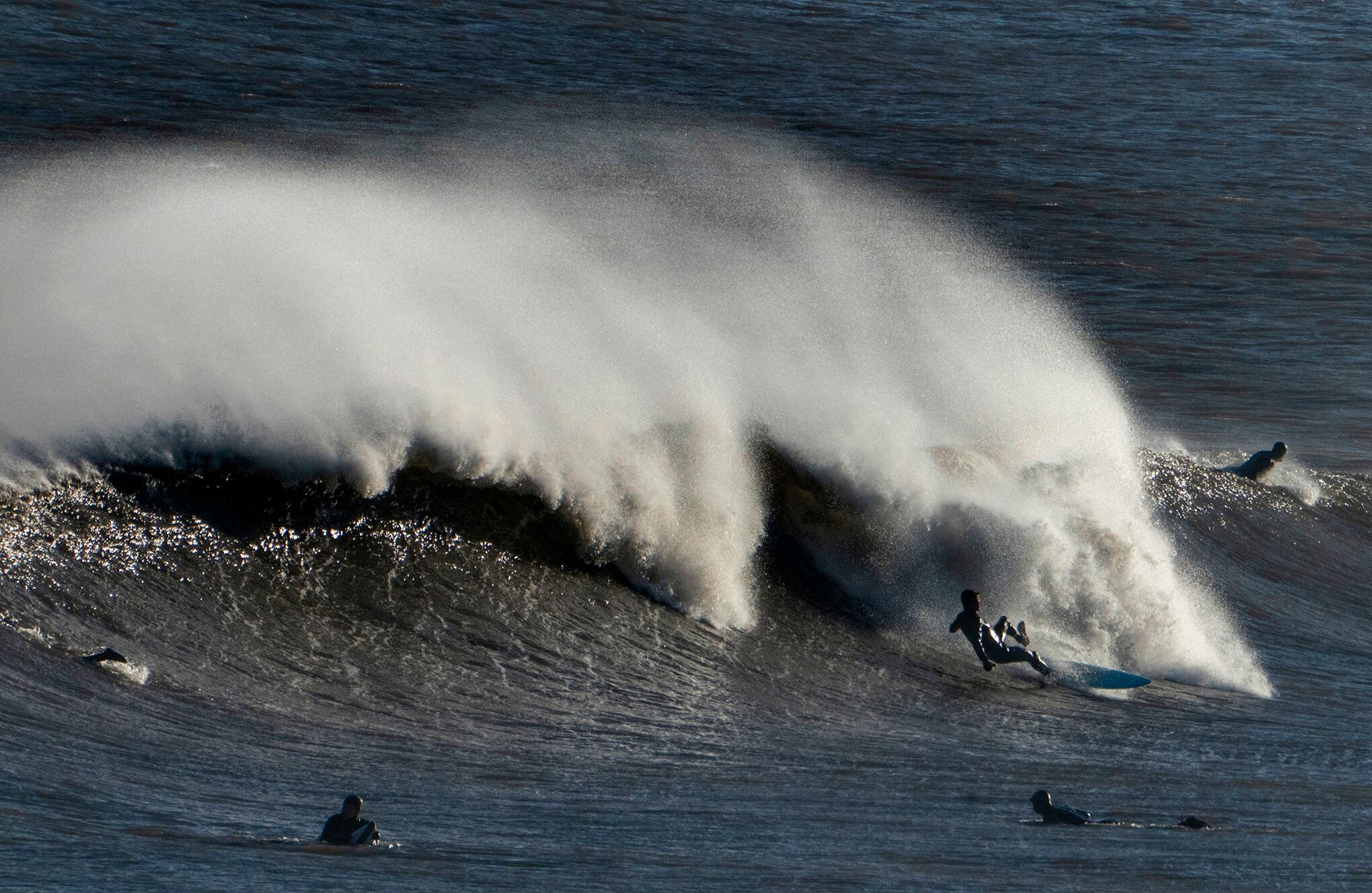 Los surfistas surcan las olas en la playa de Tynemouth, en Tynemouth, Inglaterra, el viernes 22 de enero de 2021 (Owen Humphreys / PA vía AP).