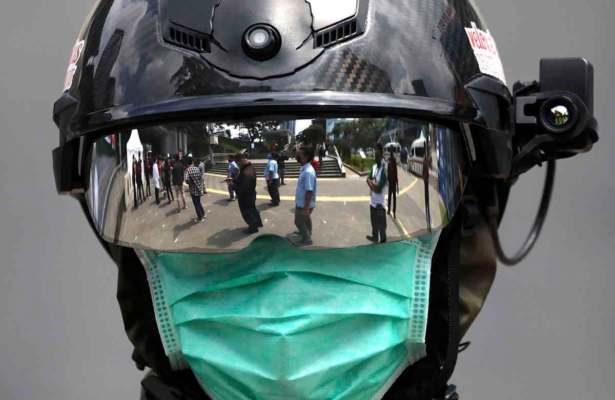 Lo que se ve en el visor de este oficial médico es el reflejo de un grupo de personas haciendo fila para hacerse la prueba del coronavirus, en Yakarta, Indonesia. 6 de mayo. Foto: Dita Alangkara/ AP