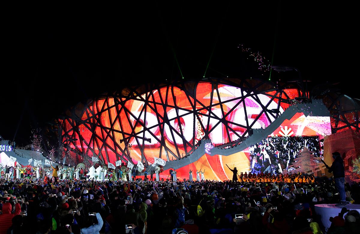 Personas de la China celebran el año nuevo frente al Estadio Nacional, iluminado con luces y en el que puede leerse “Año 2015”. (AP)