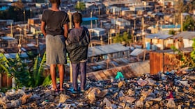 Niñas africanas de pie en la basura y mirando casas en el barrio marginal de Kibera, Kenia, África Oriental. Kibera es el barrio marginal más grande de Nairobi, el barrio marginal urbano más grande de África y el tercero más grande del mundo