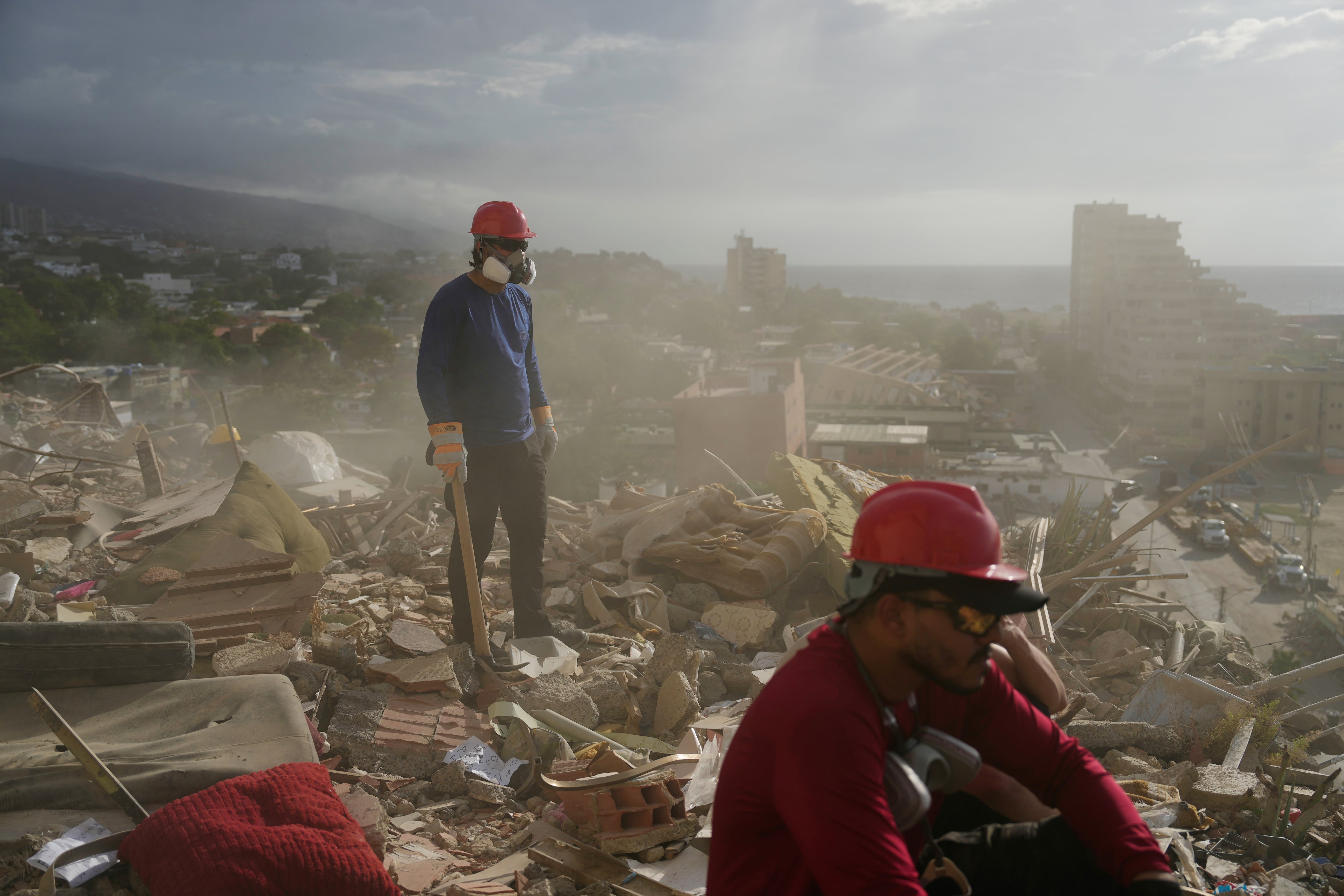 Equipos de rescate y voluntarios buscan entre los escombros de un edificio derrumbado durante los terremotos en La Guaira, Venezuela.