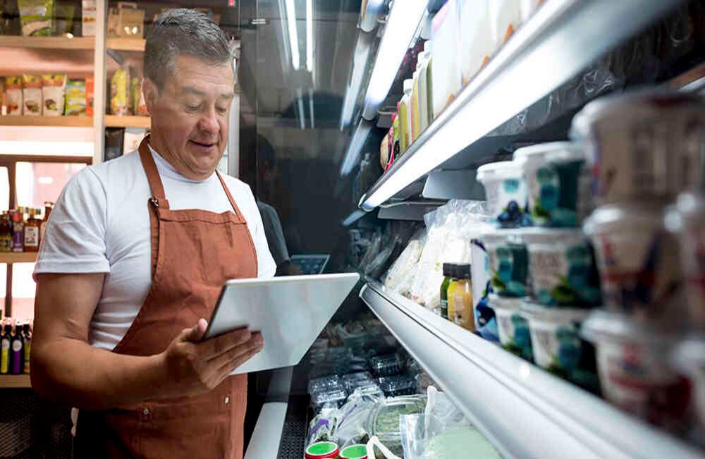 Hombre hace inventario en su pequeño negocio de comestibles.