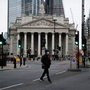 A man crosses the street backdropped by the Royal Exchange in the City of London financial district in London, Jan. 5, 2021, on the first morning of England entering a third national lockdown since the coronavirus outbreak began. British Prime Minister Boris Johnson on Monday night announced a tough new stay-at-home order that will last at least six weeks, as authorities struggle to stem a surge in COVID-19 infections that threatens to overwhelm hospitals around the U.K. (AP Photo/Matt Dunham)