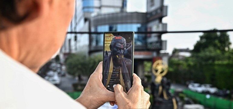 Una enorme estatua negra de un una figura alada, demacrada, con colmillos dorados y garras escarlatas, mira con furia hacia una concurrida calle de Bangkok, su repentina aparición activa la alarma y pide su eliminación. (Foto de Lillian SUWANRUMPHA )
