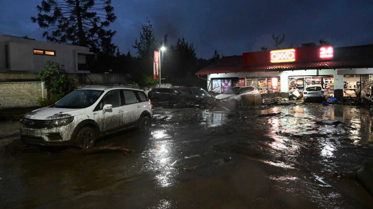 Vehículos dañados por un deslizamiento de tierra se observan frente a una tienda de conveniencia OXXO en el distrito de Las Condes, Santiago.