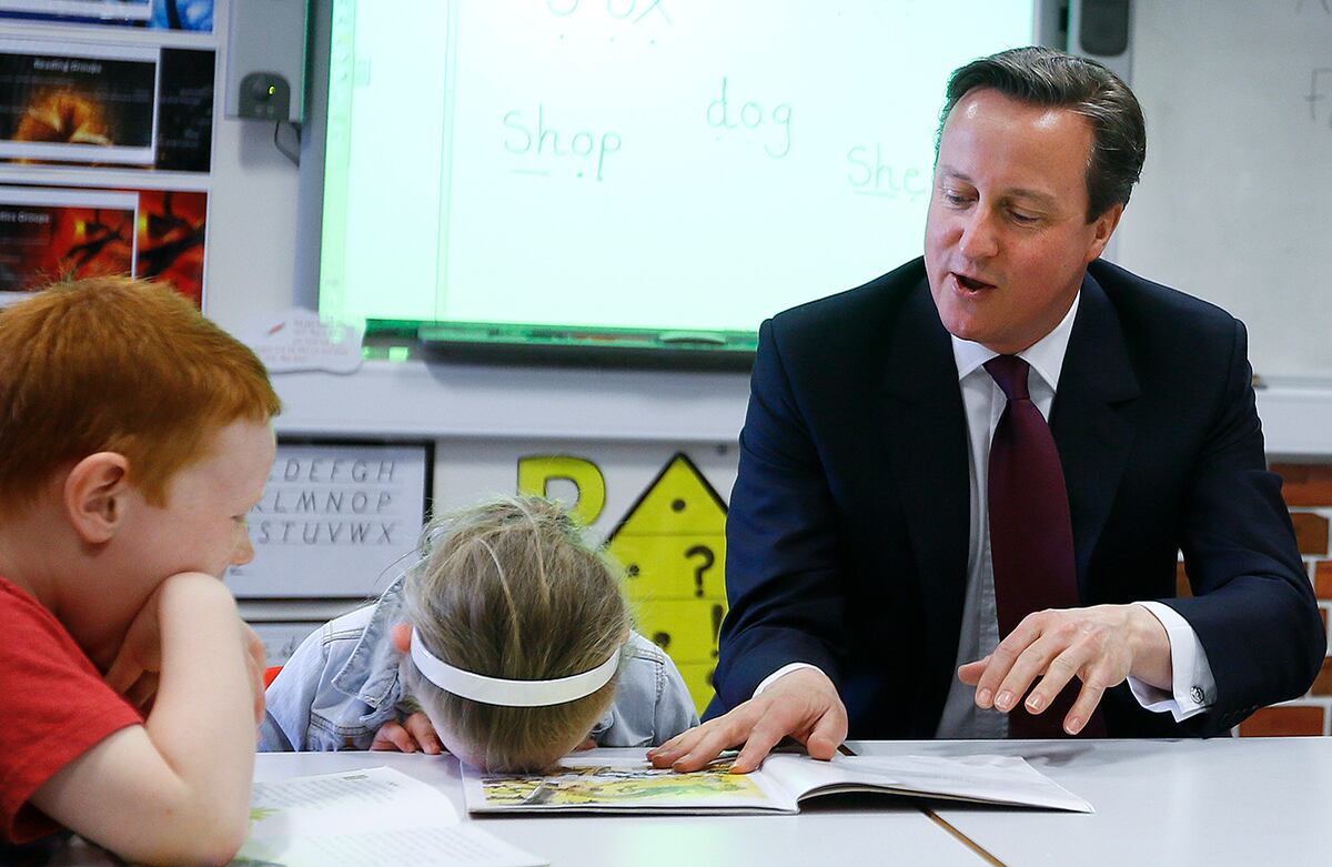 El primer ministro británico David Cameron lee un libro a dos niños en la escuela primaria de Westhoughton, Inglaterra. El próximo 7 de mayo serán las elecciones generales del Reino Unido. (AP)