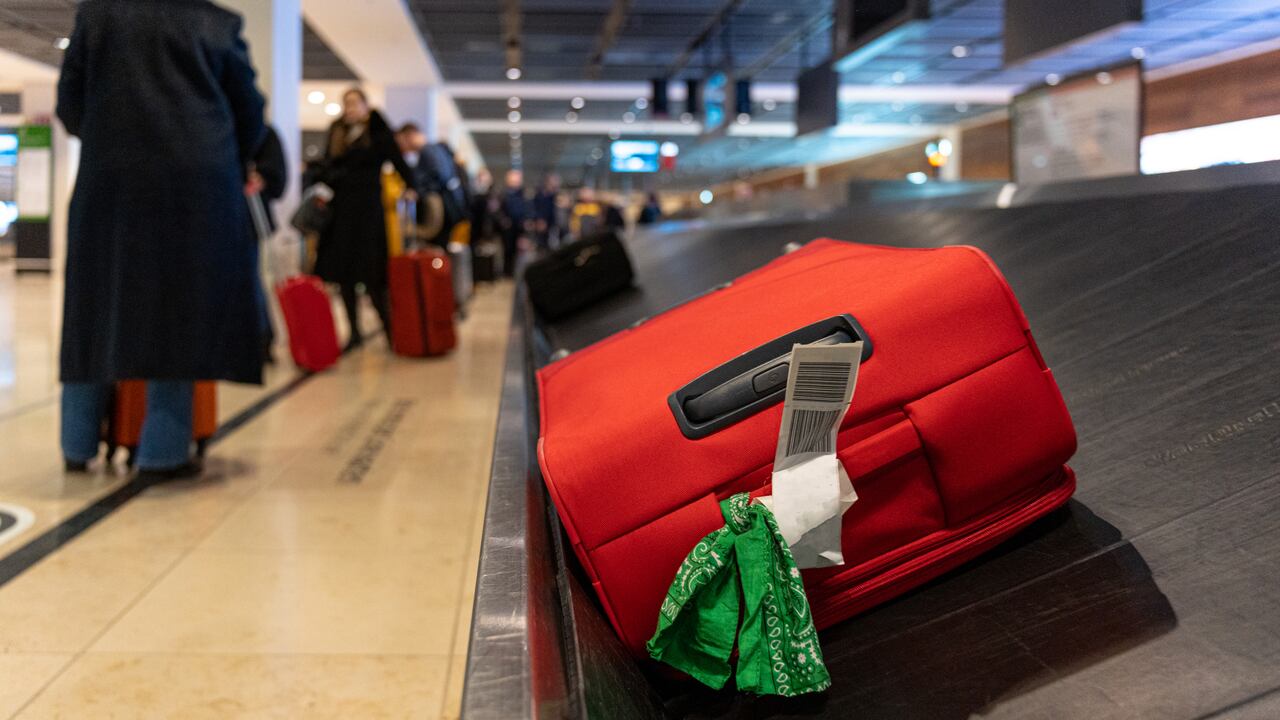 Maleta roja moviéndose sobre la cinta transportadora en el reclamo de equipaje en el aeropuerto