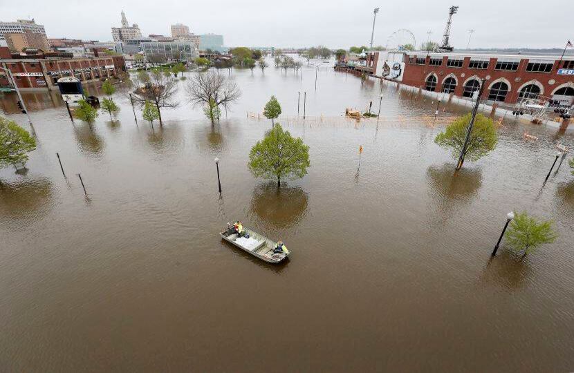 2 de mayo - Los trabajadores de la ciudad de Davenport transportan sacos de arena a través de las inundaciones del río Mississippi hasta el edificio Rivers Edge. FOTO: Kevin E. Schmidt / Quad City Times a través de AP