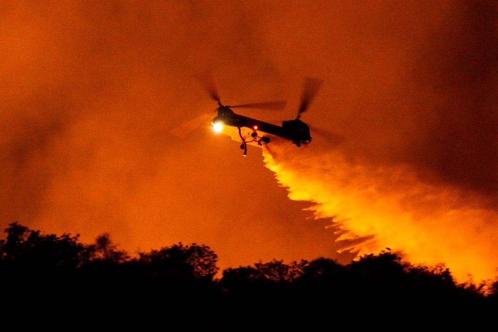 Un helicóptero arroja agua sobre el incendio Palisades en Mandeville Canyon, el sábado 11 de enero de 2025, en Los Ángeles. (Foto AP/Etienne Laurent)