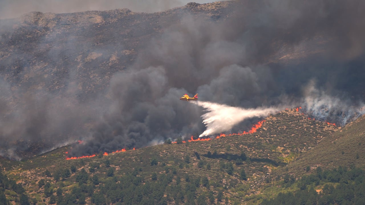 Un avión arroja agua sobre un incendio activo cerca de La Adrada, en la provincia de Ávila, España.