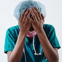 Crying nurse covering her face with hands, she is tired of working extra hours and seeing suffering and dying people