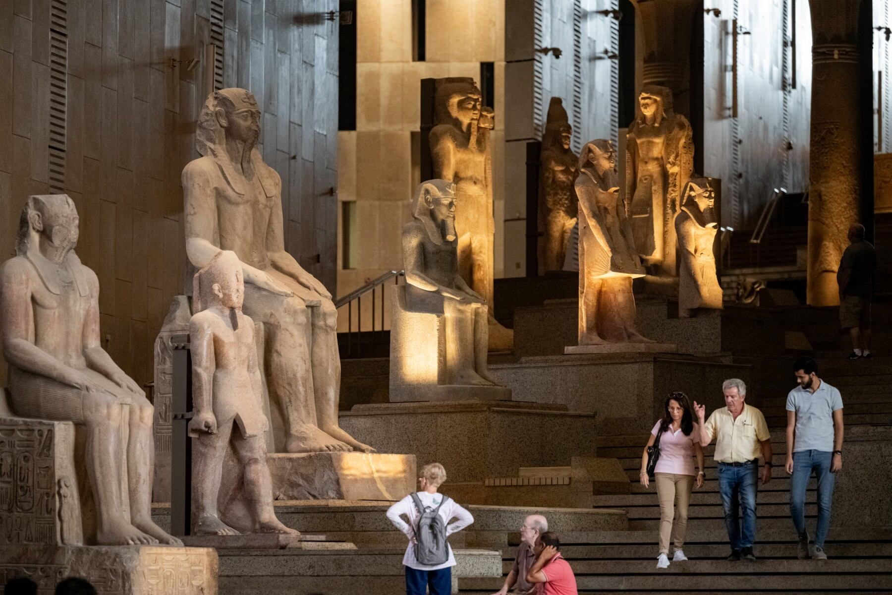 Los visitantes pasan junto a colosales estatuas del antiguo Egipto a lo largo de la Gran Escalera del Gran Museo Egipcio en Giza el 15 de octubre de 2024. (Foto de Khaled DESOUKI / AFP)