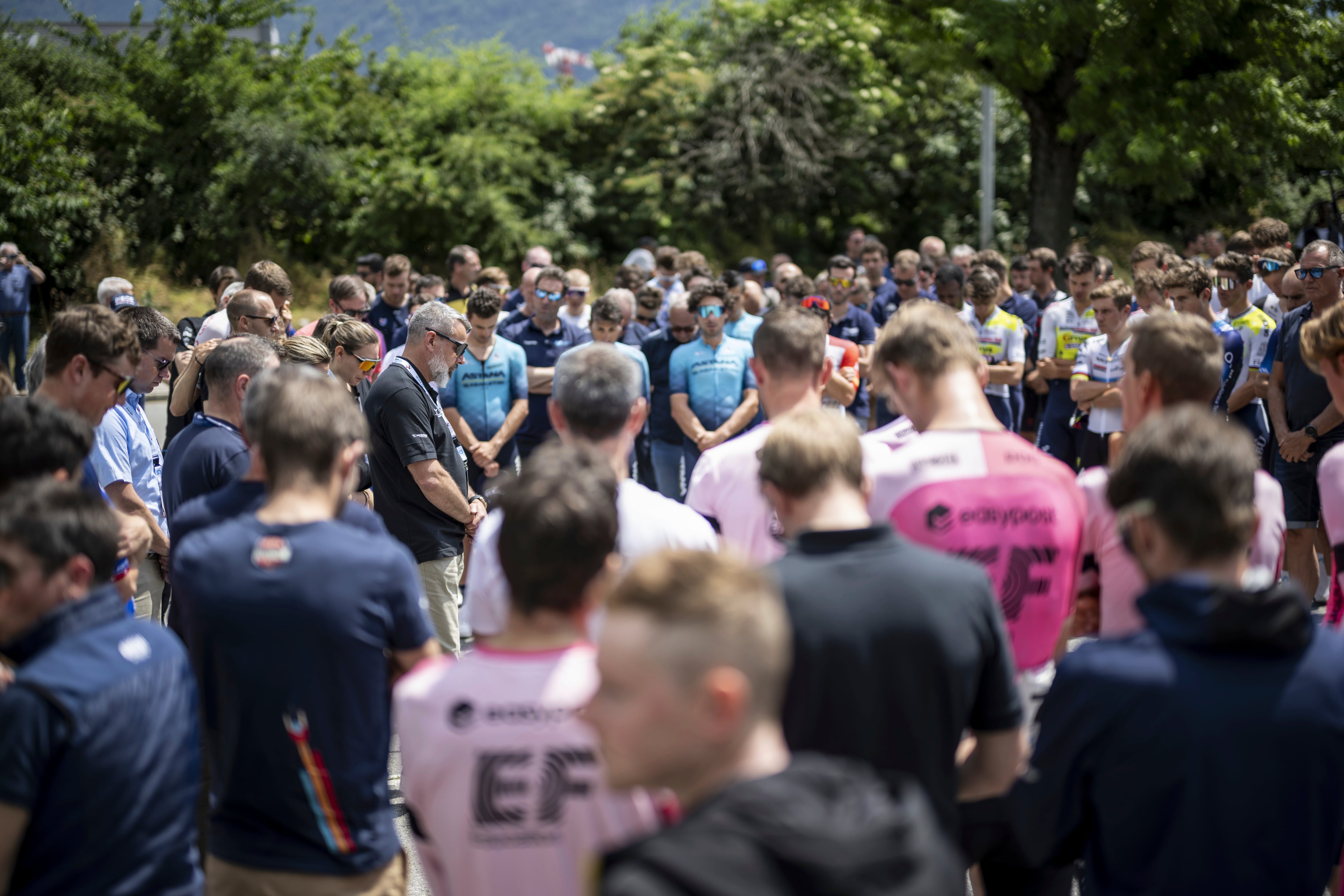 Event director Olivier Senn, center left, holds a minute of silence in honour of Gino Maeder from Switzerland of Bahrain-Victorious, who died following his crash the day before, at the 86th Tour de Suisse UCI World Tour cycling race, in Chur, Switzerland, Friday, June 16, 2023. (Gian Ehrenzelle/Keystone via AP)