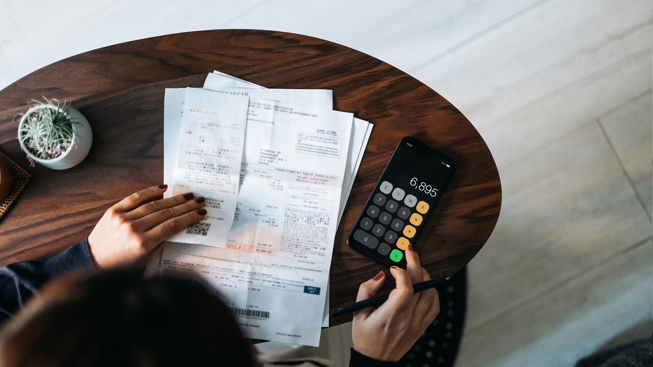 Foto de referencia de facturas en medio de una persona haciendo cálculos