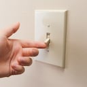 Mano apagando el interruptor de la luz de la pared. imagen en color en orientación horizontal