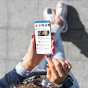 Mujer que usa la aplicación de microblogging de redes sociales en su teléfono inteligente