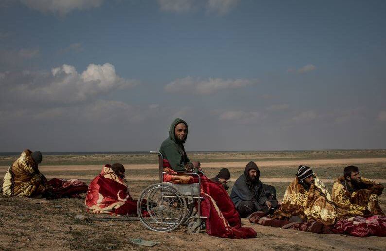 BAGOUZ, SIRIA - 9 DE FEBRERO: Los hombres que han huido luchando en Bagouz esperan en el desierto después de ser examinados por miembros de las Fuerzas Democráticas Sirias (SDF) en un punto de detección improvisado en el desierto el 9 de febrero de 2019 en Bagouz, Siria. FOTO: Chris McGrath / Getty Images