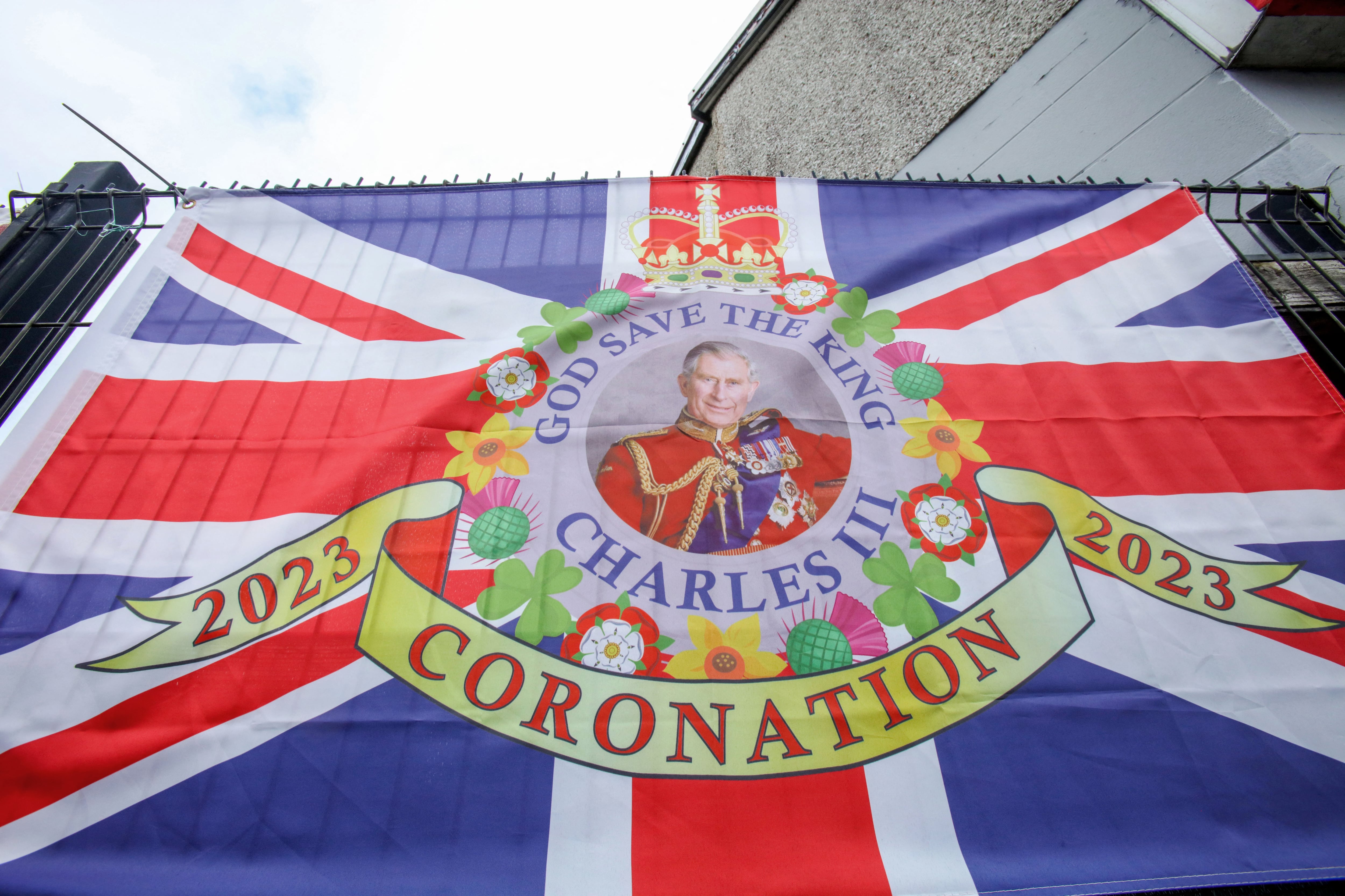 A Union flag with a photograph of Britain's King Charles III is displayed in a street in Larne, north of Belfast in Northern Ireland on May 5, 2023, in the build-up to the coronation weekend. (Photo by Paul Faith / AFP)