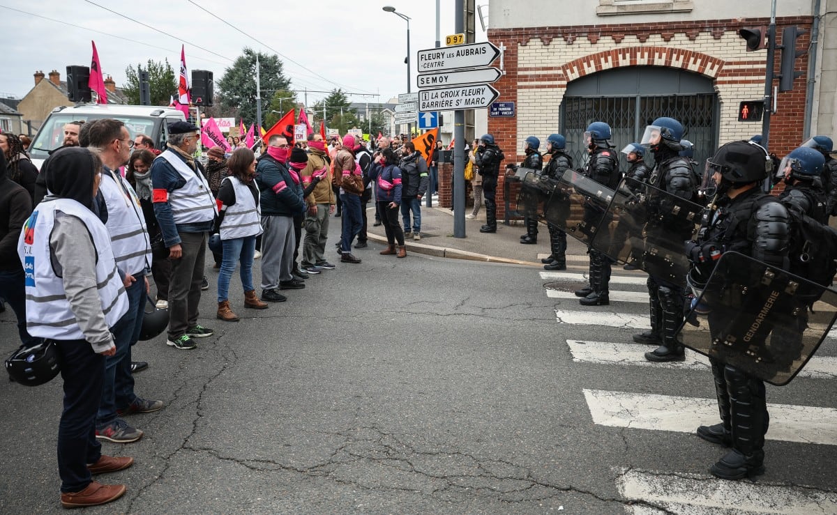Manifestantes, entre ellos miembros de los sindicatos FSU y Sud Solidaires, se encuentran frente a gendarmes franceses en una carretera agrietada durante una protesta.