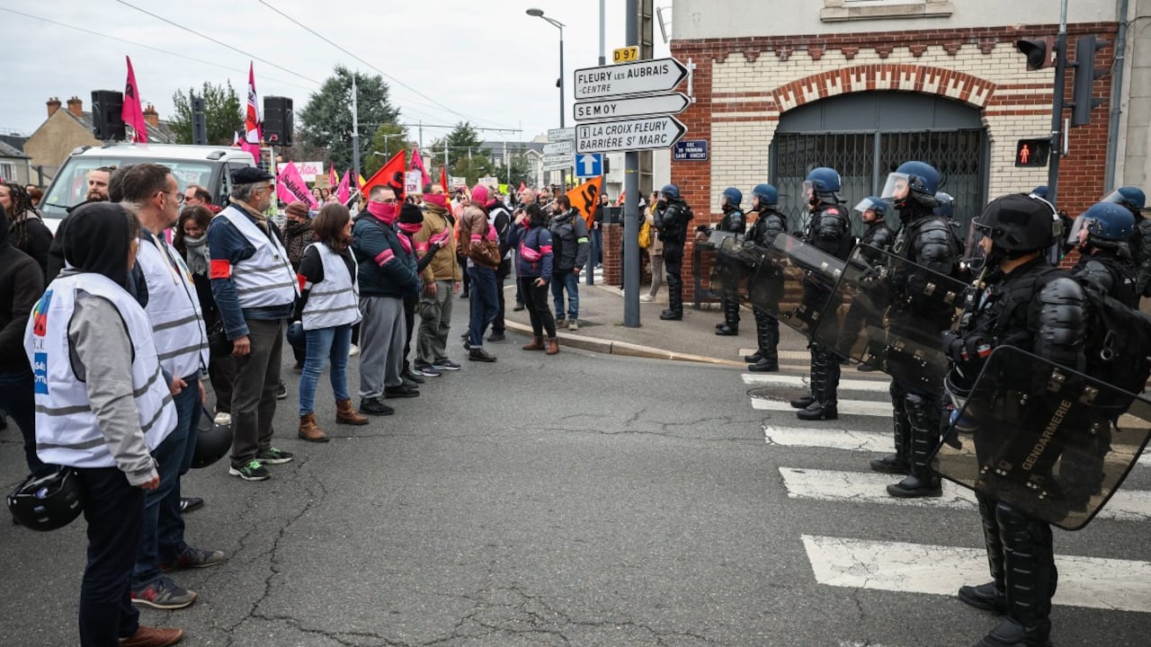 Manifestantes, entre ellos miembros de los sindicatos FSU y Sud Solidaires, se encuentran frente a gendarmes franceses en una carretera agrietada durante una protesta.