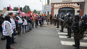 Manifestantes, entre ellos miembros de los sindicatos FSU y Sud Solidaires, se encuentran frente a gendarmes franceses en una carretera agrietada durante una protesta.