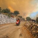 La gente se aleja de un incendio que avanza en la aldea de Cokertme, en Bodrum, Mugla, Turquía, el lunes 2 de agosto de 2021. Por sexto día consecutivo, los bomberos turcos lucharon el lunes para controlar los incendios que arrasan los bosques cercanos a las playas de Turquía. Alimentados por fuertes vientos y temperaturas abrasadoras, los incendios que comenzaron el miércoles dejaron ocho muertos y obligaron a residentes y turistas a huir de los centros vacacionales en una flotilla de pequeñas embarcaciones. Foto: AP / Emre Tazegul.