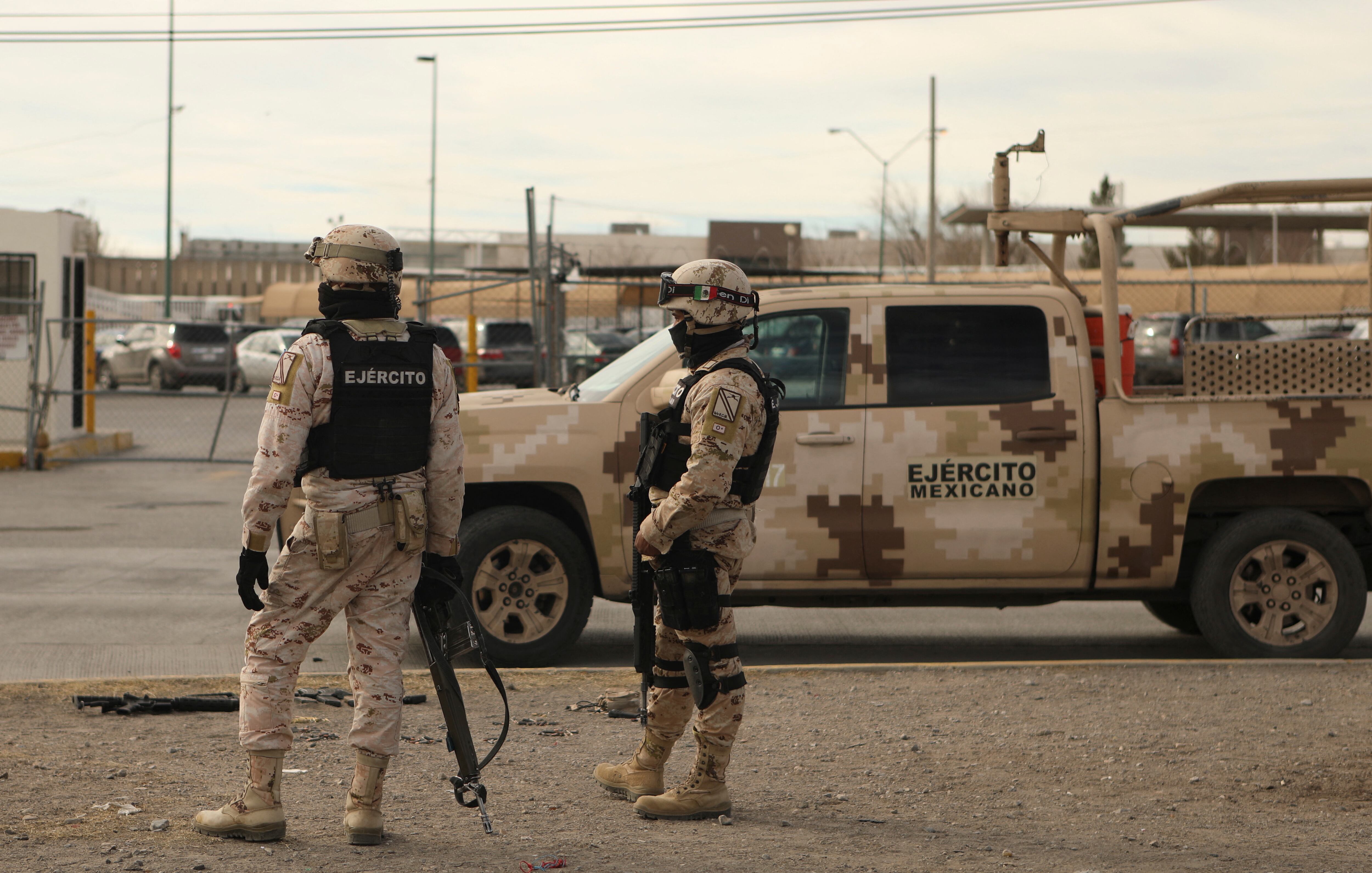 Miembros del Ejército Mexicano junto a un rifle semiautomático (L, en el piso) y cartuchos encontrados afuera de la prisión de Ciudad Juárez luego de un ataque en Ciudad Juárez, estado de Chihuahua, el 1 de enero de 2023. - Hombres armados atacaron una prisión en la norteña ciudad mexicana de Ciudad Juárez el domingo, dejando 14 muertos y permitiendo la fuga de 24 reclusos, dijo la fiscalía del estado de Chihuahua. Un número desconocido de hombres armados a bordo de vehículos blindados participó en el ataque, y entre los muertos había diez oficiales penitenciarios y agentes de seguridad, dijo en un comunicado. (Foto por HERIKA MARTÍNEZ / AFP)