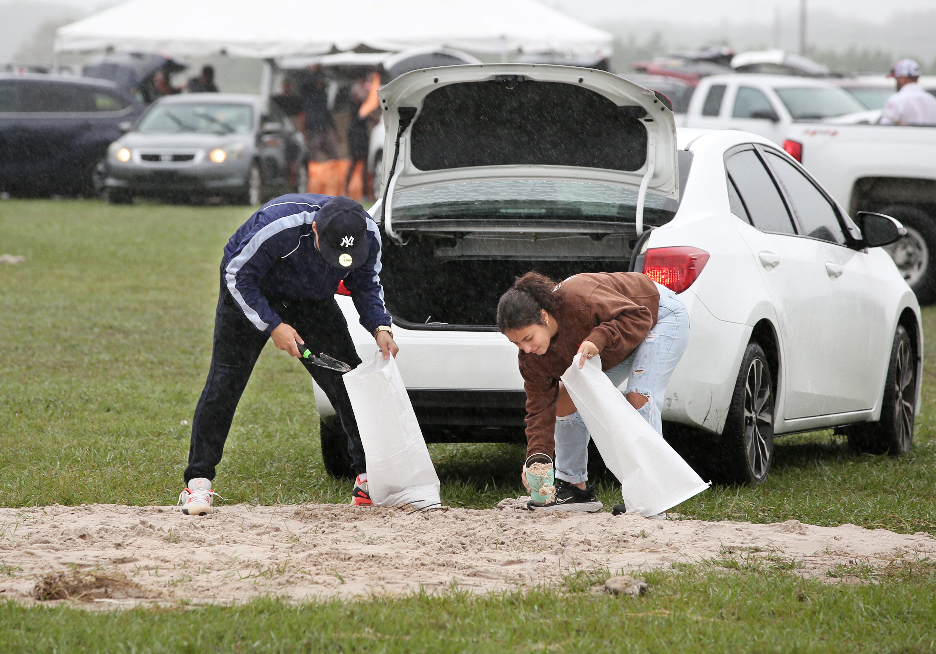 Ciudadanos en la Florida ponen bolsas de arena para apaciguar lluvias ante la amenaza del huracán Milton.