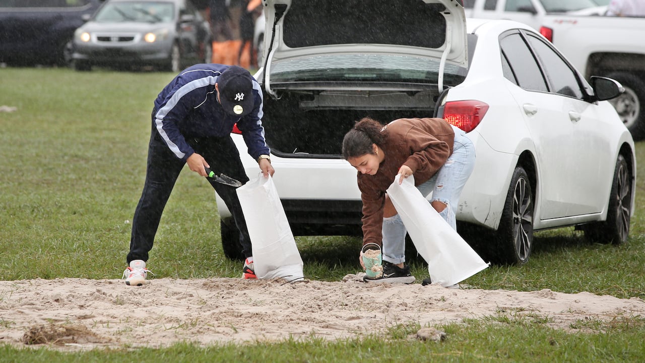 Ciudadanos en la Florida ponen bolsas de arena para apaciguar lluvias ante la amenaza del huracán Milton.