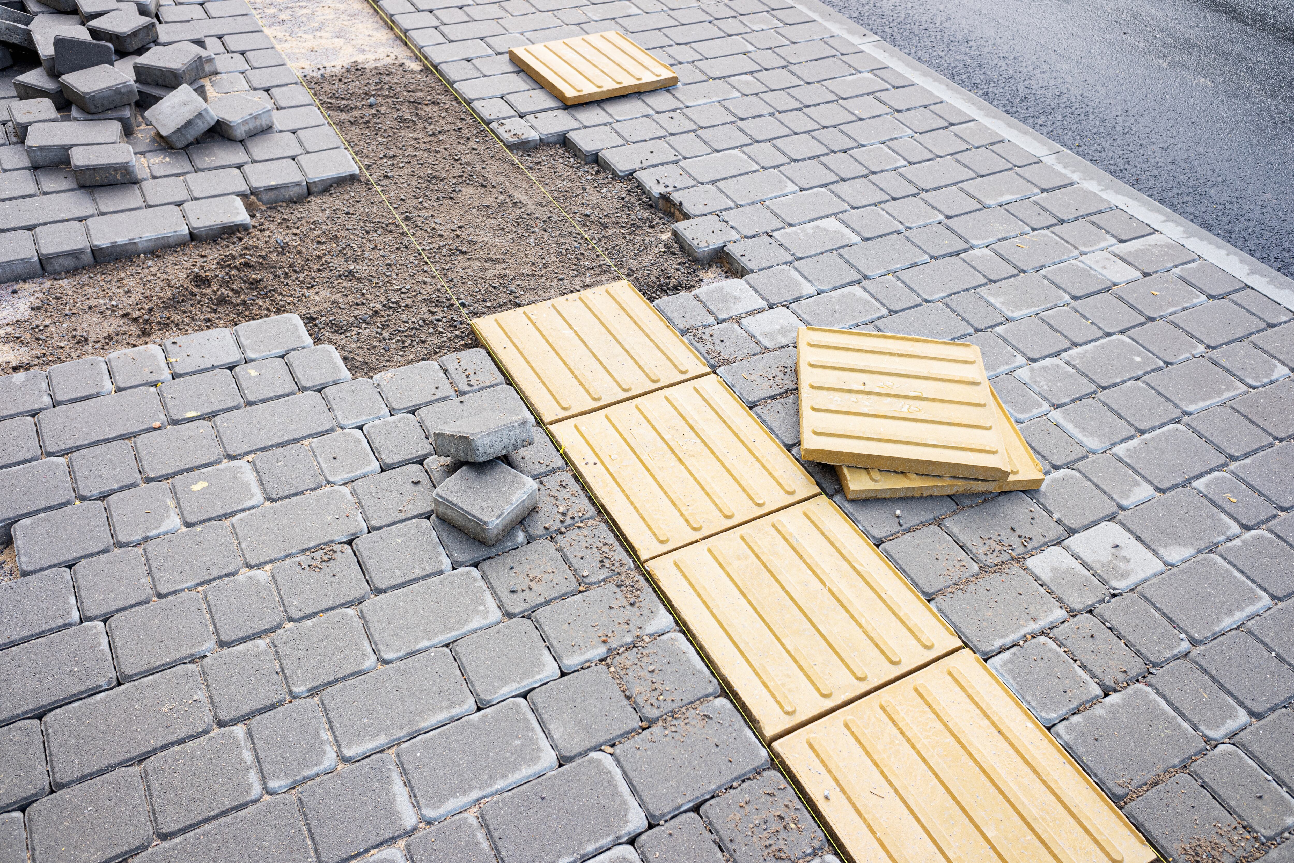 Pedestrian walking on tactile paving on footpath