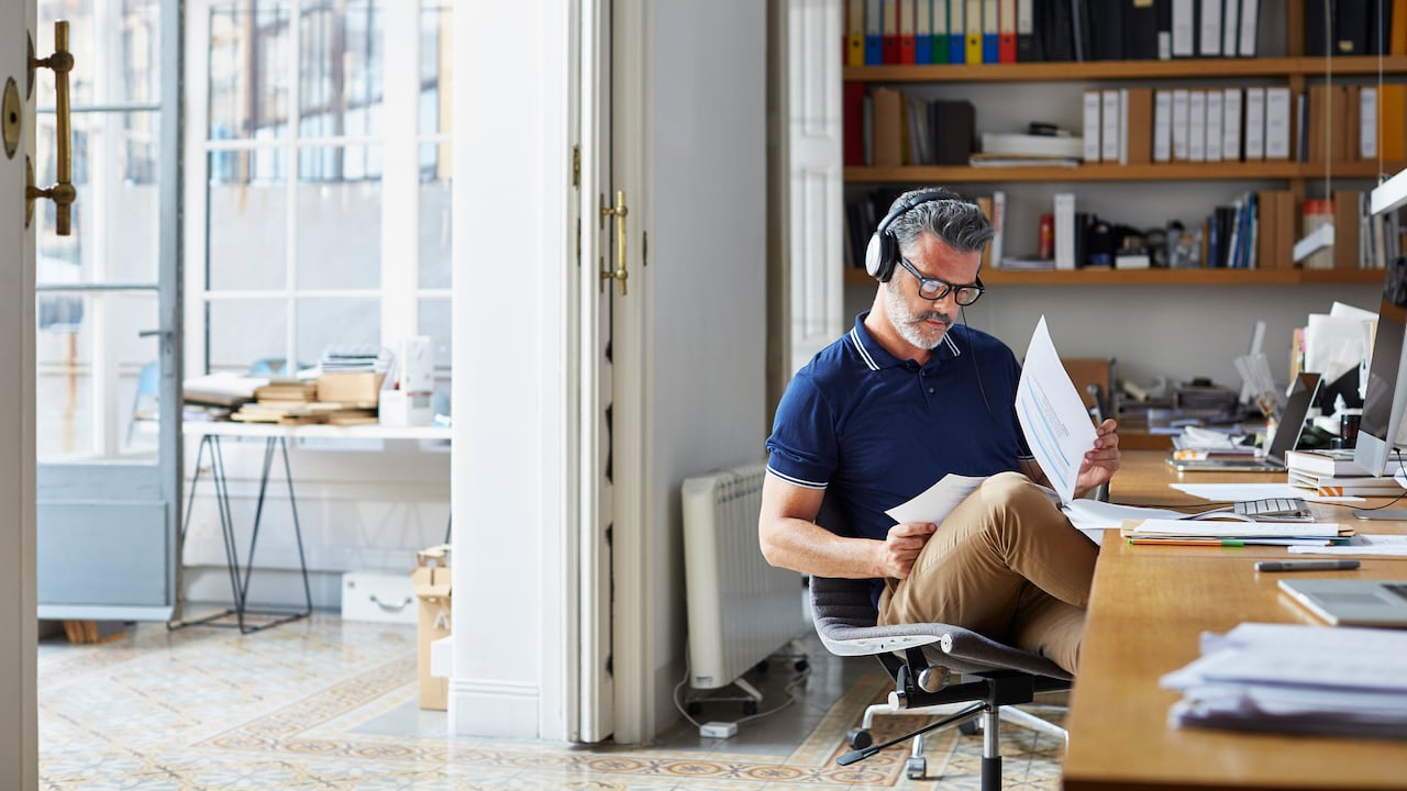 Mature businessman examining documents at desk in office