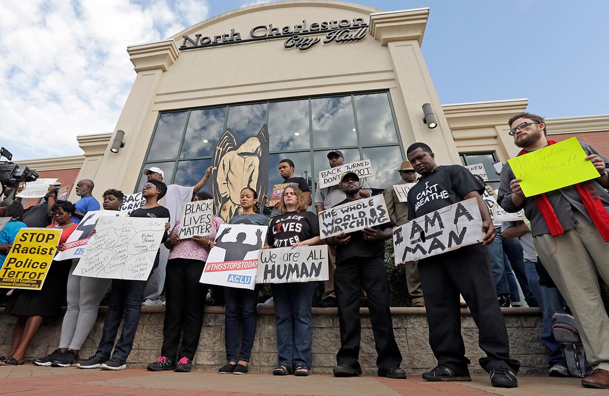 Los manifestantes permanecen en silencio para protestar por el asesinato de Walter Scott por un policía que lo detuvo en el tráfico en Carolina del Sur, EE. UU.. Algunos avisos dicen: "Alto al terrorismo racista policiaco", "todos somos humanos". (AP)