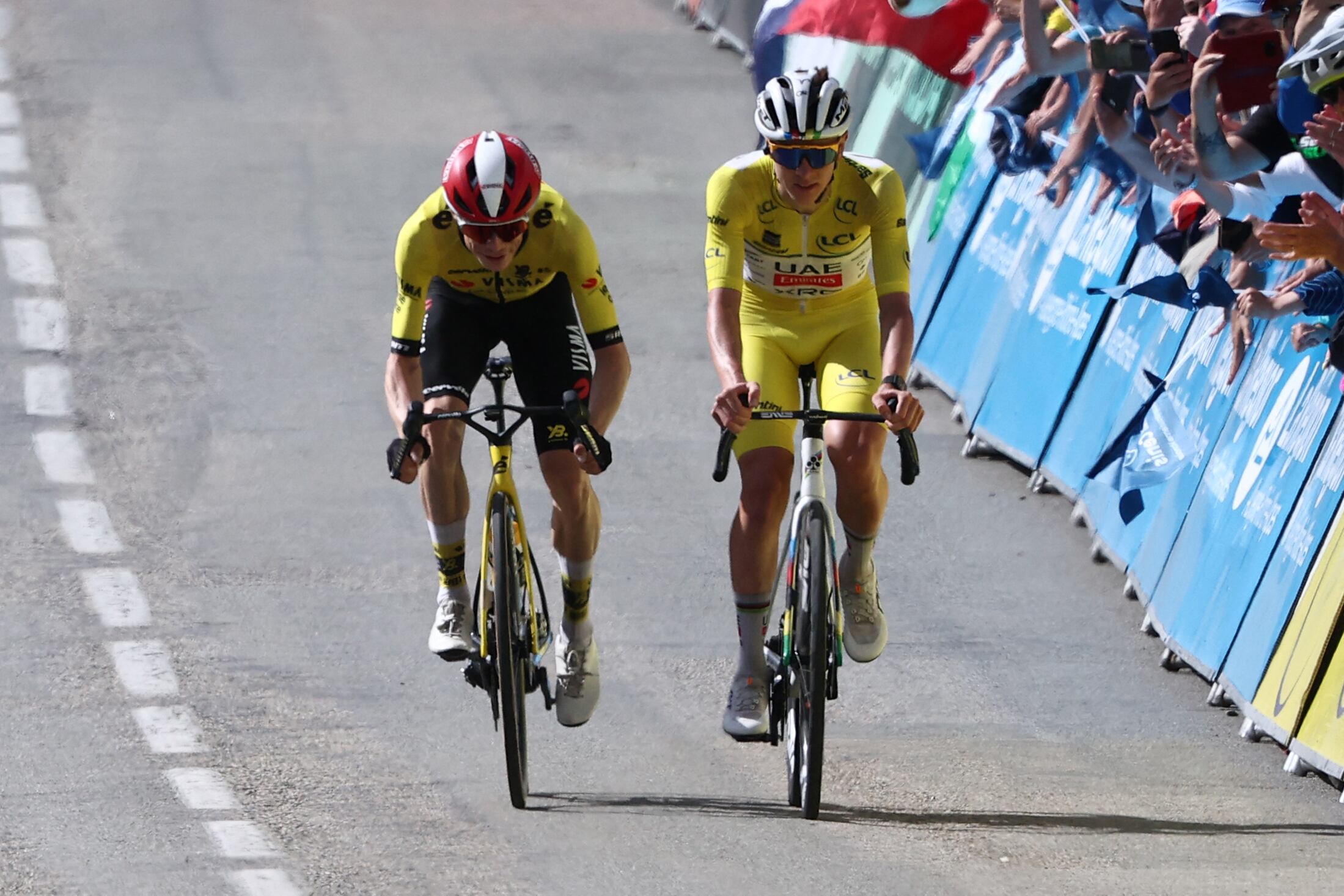 El ciclista danés Jonas Vingegaard (izq.) del Lease a Bike y el ciclista esloveno Tadej Pogacar del UAE Team Emirates XRG luciendo el maillot amarillo de líder de la general pedalean hacia la línea de meta de la octava y última etapa.