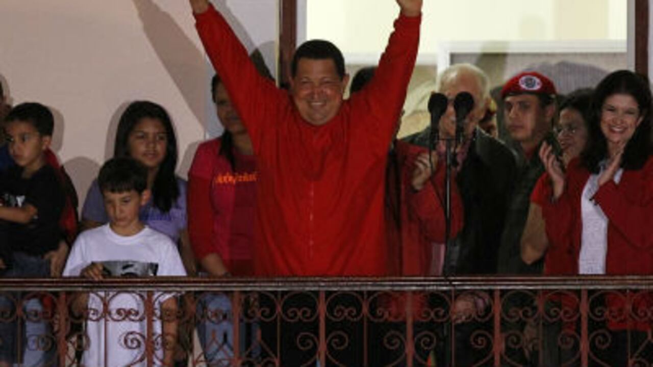 El presidente de Venezuela, Hugo Chávez (d), saluda desde un balcón del palacio de Miraflores, en Caracas (Venezuela) tras ser declarado vencedor las elecciones.
