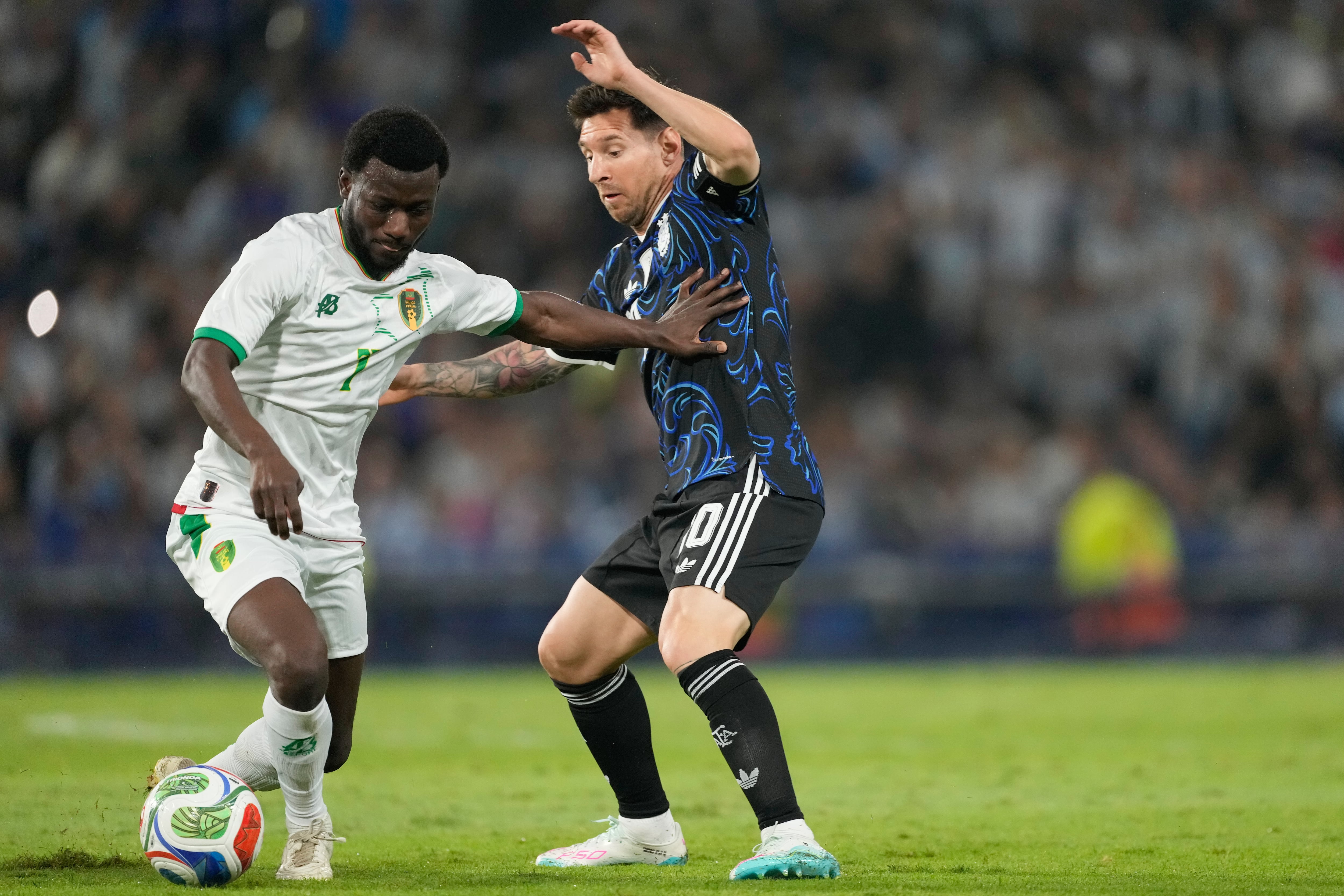 Aboubakary Koita, de Mauritania, y Lione Mesi, de Argentina, disputan el balón durante un partido amistoso de fútbol en Buenos Aires, Argentina.