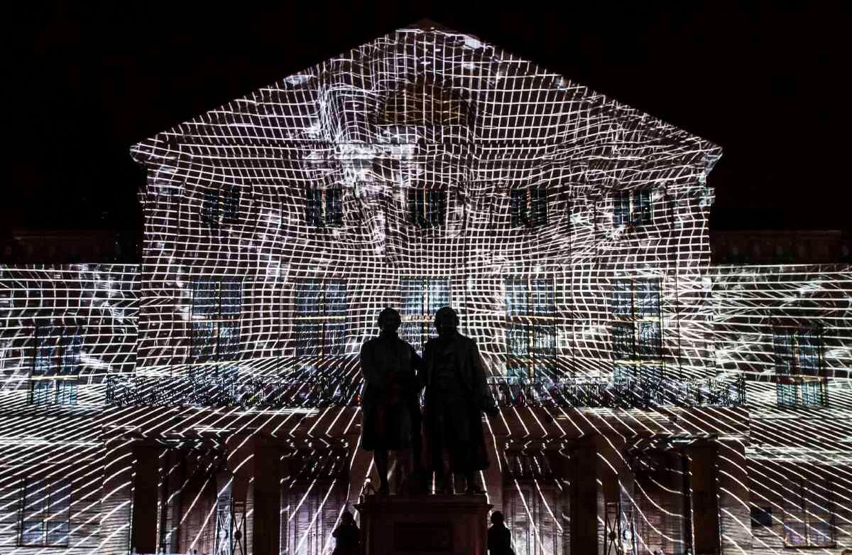 El monumento a los poetas alemanes Johann Wolfgang von Goethe, a la izquierda, y Friedrich Schiller, a la derecha, se levanta al frente de la fachada 'REMAKE 3', proyectada por ruestungsschmie.de y Soundselektor, en el Teatro Nacional Alemán durante el festival Genius Loci en Weimar, Alemania, el domingo 11 de agosto de 2019. El Genius Loci Weimar es un festival anual de proyecciones multimedia. (Foto AP / Jens Meyer)