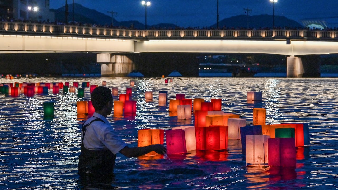 Un voluntario empuja linternas de papel hacia el río Motoyasu después de que los visitantes las soltaran para conmemorar el 80.º aniversario del primer ataque con bomba atómica del mundo, en la ciudad de Hiroshima el 6 de agosto de 2025. (Foto de Richard A. Brooks / AFP)
